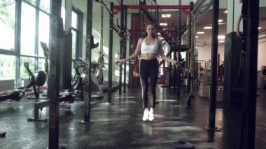 Spor salonunda ip atlama egzersizi yapan genç bir kadın. Sporcu kadın spor salonunda sıkı çalışıyor..