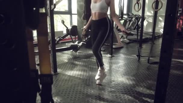 운동을 하는 젊은 여성은 체육관에서 줄넘기를 한다. 체육관에서 열심히 훈련하는 운동 선수 여성. — 비디오