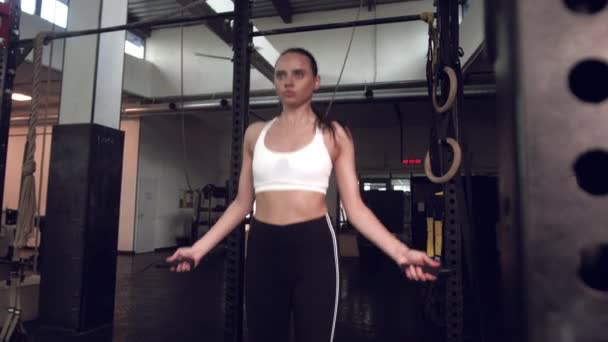 운동을 하는 젊은 여성은 체육관에서 줄넘기를 한다. 체육관에서 열심히 훈련하는 운동 선수 여성. — 비디오