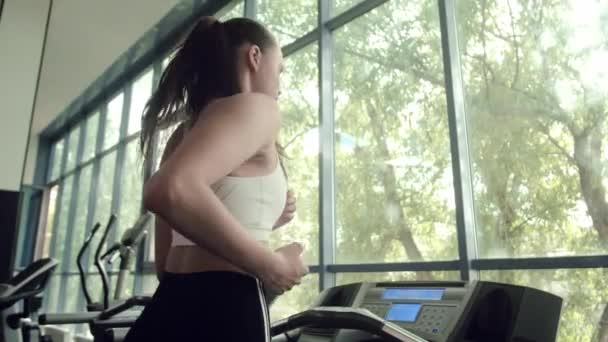 파노라마 창에서 러닝 머신 위를 달리는 여자. 건강 한 생활 방식에 대한 개념. — 비디오