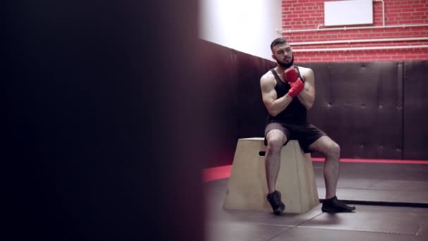 Kickbox combattant musculaire avec bandages rouges sur le fond d'un mur de briques — Video