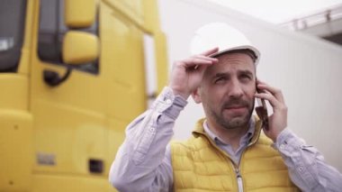 Kasketli ve çelik yelekli bir karavan sürücüsü. İşçi portresini kapat.