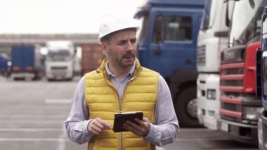 Kasketli ve çelik yelekli bir karavan sürücüsü. İşçi portresini kapat.