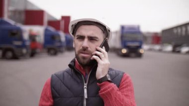 Kasketli ve çelik yelekli bir karavan sürücüsü. İşçi portresini kapat.