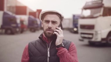 Kasketli ve çelik yelekli bir karavan sürücüsü. İşçi portresini kapat.