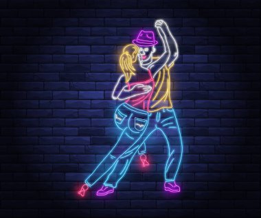 Dans partisi neon pankartı ve dans eden bir çift. Latin dansçıların parlak ışıklı neon işaretleri. Duvarın arka planında neon harfler var. Gece hayatı ve eğlence tabelası.