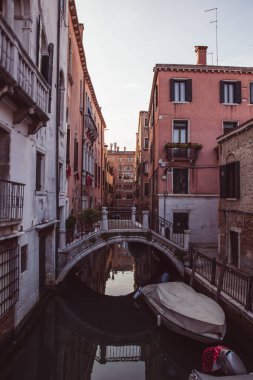 Venedik 'in boş sokakları ve köprüleri, küçük bir köprü ve pembe turuncu evler Venedik, İtalya' da günbatımında demirlemiş geleneksel bir gondol üzerinde yansıyor. Tecrit, karantina.