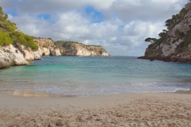 Güney minorka koyunda kayaların arasında bir sürü bitki örtüsü ve şeffaf sular bulunur.
