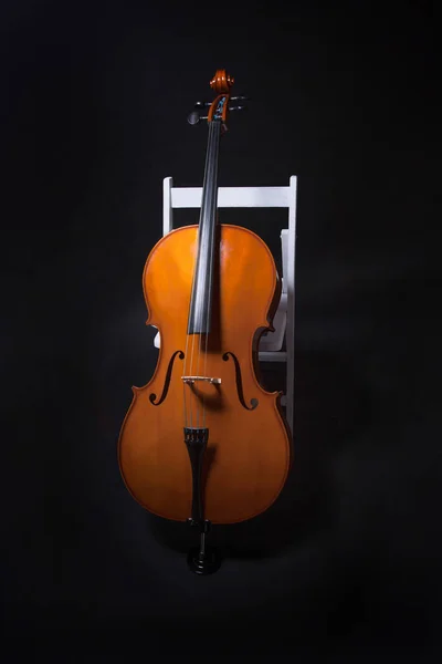 Violoncello Appoggiato Sedia Bianca Sfondo Nero — Foto Stock