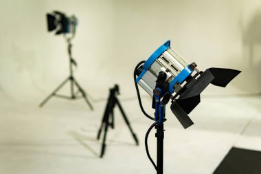 Bir film, televizyon ya da fotoğraf stüdyosunda tripodun üzerinde eski model fresk ışığı. Gri ve mavi. Arkada bir tane daha var, ikisi de kapalı. Beyaz ve boş film seti. 