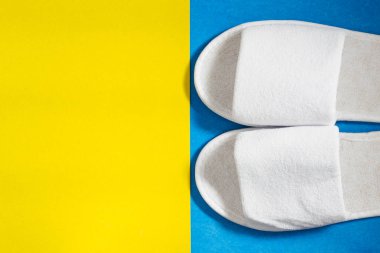 Mavi ve sarı arka planda beyaz terlikler. Üst görünüm, metin için boşluk kopyala