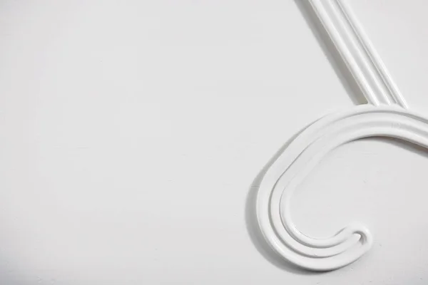 Part of a white clothes hanger on a white wooden background. Top view, copy space for text — Stock Photo, Image
