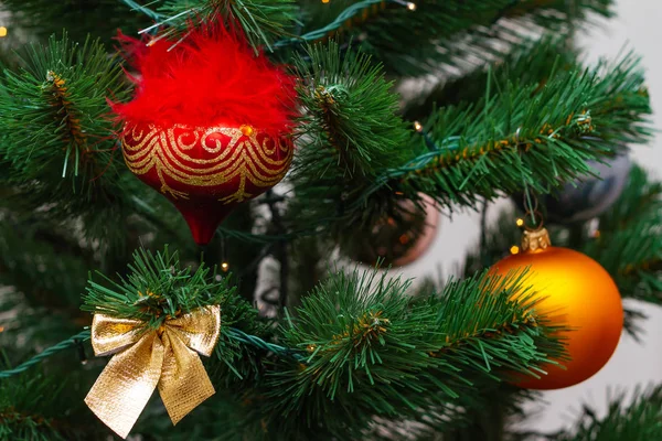 赤とオレンジのボールを持つクリスマスツリーの一部、フェイククリスマスツリー上の金の弓。新年カード、選択的フォーカス — ストック写真
