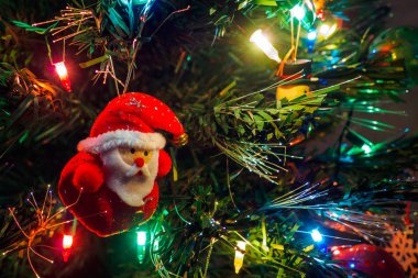 Noel Baba 'nın asılı oyuncağı ve çelenk ışıklarıyla Noel ağacı. Yeni yıl kartı, seçici odaklanma