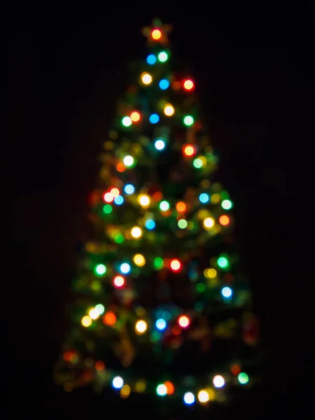 暗闇の中でガーランドとぼやけたクリスマスツリーの垂直方向のビュー。要約集光照明付きクリスマス背景 — ストック写真