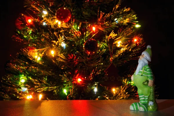 Figura de Papá Noel en ropa verde sobre fondo árbol de Navidad con luces de guirnalda. Copiar texto, enfoque selectivo — Foto de Stock