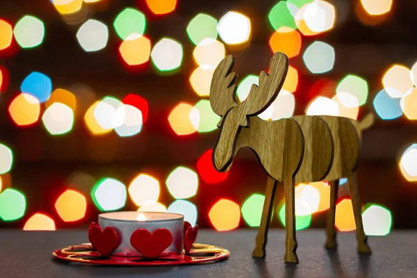 Elk figurita de madera y vela de té en el fondo de luces de colores bokeh. Enfoque selectivo — Foto de Stock