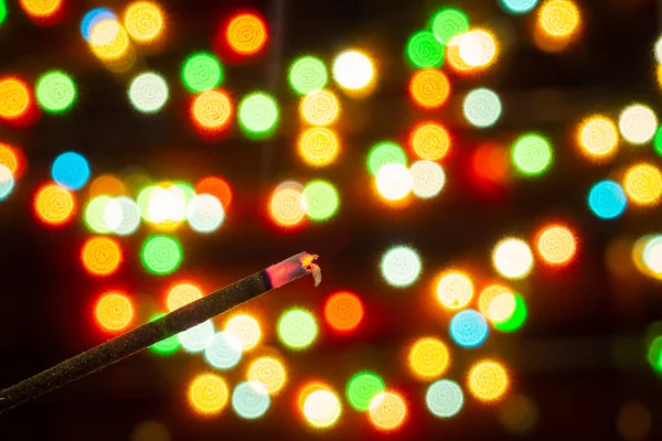 Vara de incenso no fundo do bokeh de luzes coloridas de guirlandas, fundo borrado, foco seletivo — Fotografia de Stock