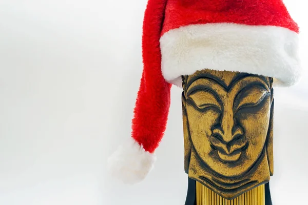 Buda 'nın tahta yüzü Noel Baba şapkasıyla beyaz arka plan, seçici odak, kopyalama alanı