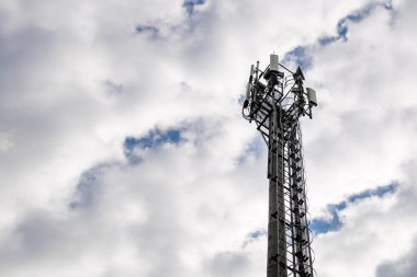 Bulutlu gökyüzü arkaplanındaki hücresel iletişim kulesi, boşluğu kopyala