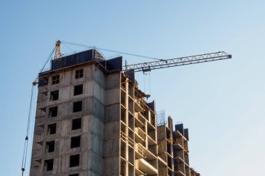 Yüksek panelli bina inşaatı, mavi gökyüzünün arka planında inşaat vinci