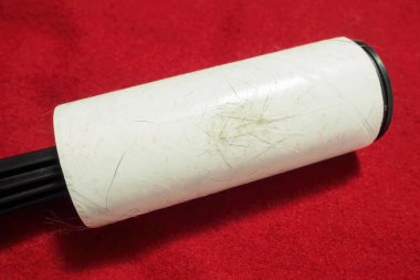 Kırmızı kumaş üzerinde hayvan tüyü olan iplik çıkarıcı, üst görünüm.