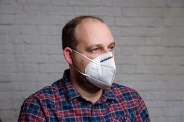 KN-95 koruma maskesi takan genç bir adam. Virüs ve salgın hastalığın yayılmasını önlemek için koruyucu ağız filtresi maskesi. Hastalıklar, grip, hava kirliliği, corona virüsü konsepti