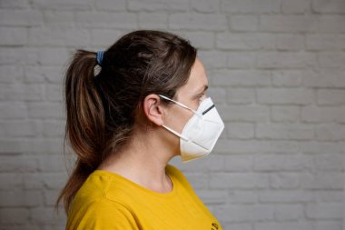 KN-95 koruma maskesi takan genç bir kadın. Virüs ve salgın hastalığın yayılmasını önlemek için koruyucu ağız filtresi maskesi. Hastalıklar, grip, hava kirliliği, corona virüsü konsepti