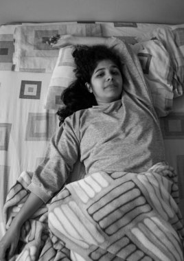 Yatakta beline sarılmış bir kadın güne başlamak için uyanıyor ve esniyor.