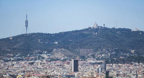 Montjuic tepesinden dağlarla çevrili Barcelona 'nın çatıları. Tibidabo dağına daha yakından bak.