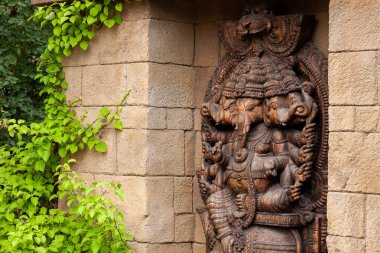 Kahverengi ahşap Ganesha tapınakta. Etrafı yeşilliklerle çevrili..