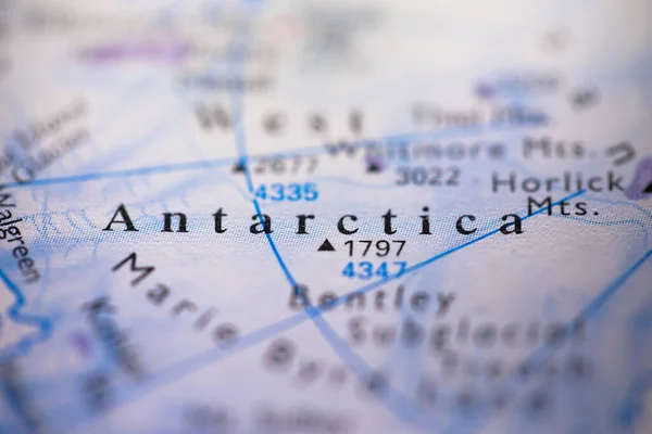 Shallow depth of field focus on geographical map location of south pole Antarctica region in Antarctic continent on atlas