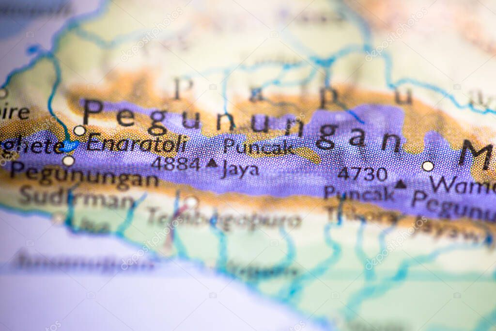 Shallow depth of field focus on geographical map location of Puncak Jaya in Irian Jaya Indonesia Asia continent on atlas