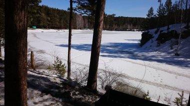 Kışın göl ağaçların arasında buz ve karla kaplıydı.