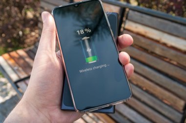 Kablolu yayın olmadan akıllı telefon erkek elinde indüksiyon güç bankasından şarj oluyor. Modern teknoloji kavramı.