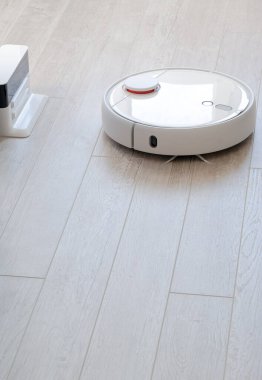 Beyaz yuvarlak robotik elektrikli süpürge laminatta - teknoloji ev işi