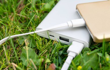 Çimenlikteki güç bankasıyla akıllı telefon şarj.