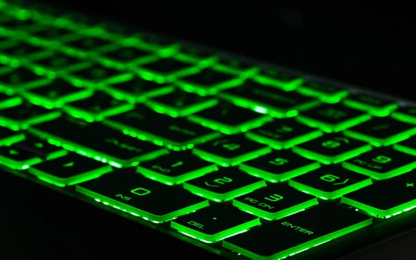 Green backlight, backlit on gaming laptops computer in the dark. Close up.