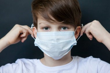 Tıbbi maske takan sevimli bir çocuk. Salgın nedeniyle karantinaya alınmış çocuklar..