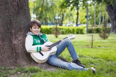 Çocuk akustik gitarıyla prova yapıyor.