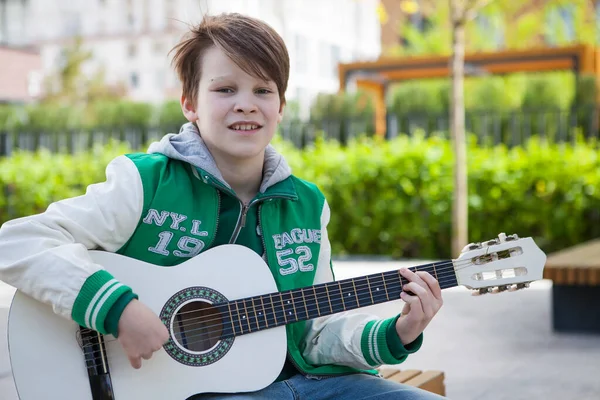 Çocuk akustik gitarıyla prova yapıyor.