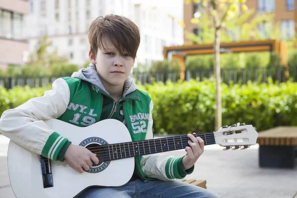 Çocuk akustik gitarıyla prova yapıyor.