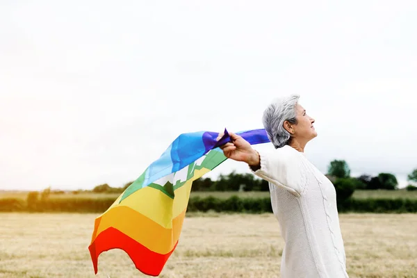 stock image Old lesbian woman with gay pride flag in a field. LGBT concept and old age.