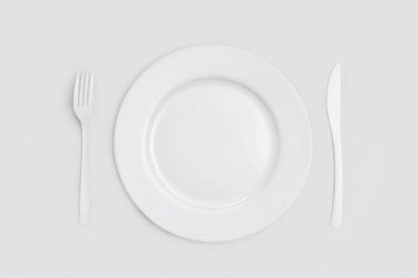 Sarı tabaklar: tabak, bıçak ve çatal. Sarı arka planda, üst tarafta. Tek Renkli