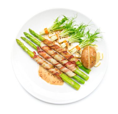 Pastırma sarılmış kuşkonmaz, sasemi soslu ızgara ve bezelye lahanası, acılı salatada rulo siyah sasemi, fırında patates, peynirli peynir, beyaz arka planda izole edilmiş.