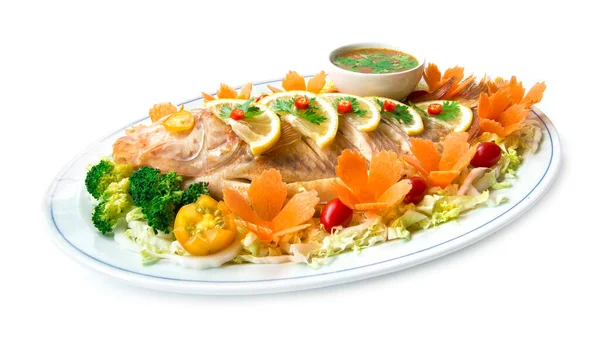 Steamed fish (Tilapia fish) in lemon sauce with Thai spicy sauce or seafood sauce in dipping bowl decorate with carved carrots tomato vegetables style healthy food, diet food side view