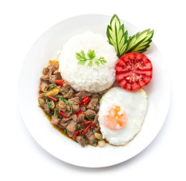 Tayland yemekleri kızarmış biftek baharatlı ve fesleğenli pilav ve kızarmış yumurta ve domates salatalığı oymalı beyaz arka planda izole edilmiş beyaz tabak