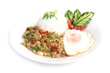 Tayland yemekleri kızarmış domuz baharatı ve fesleğenli pilav ve kızarmış yumurta ve domates salatalığı ile servis edilmiş beyaz arka plana oyulmuş beyaz tabak.