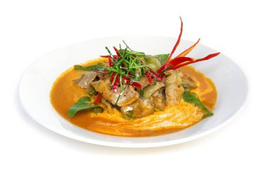 Hindistan cevizi sütü (Panang) ile kurutulmuş kırmızı körili domuz eti üzerine bergamot yaprağı dilimi ve beyaz arka planda izole edilmiş kırmızı biber sosu.