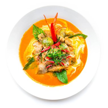 Hindistan cevizi sütü (Panang) ile kurutulmuş kırmızı körili domuz eti üzerine bergamot yaprağı dilimi ve beyaz arka planda izole edilmiş kırmızı biber sosu.